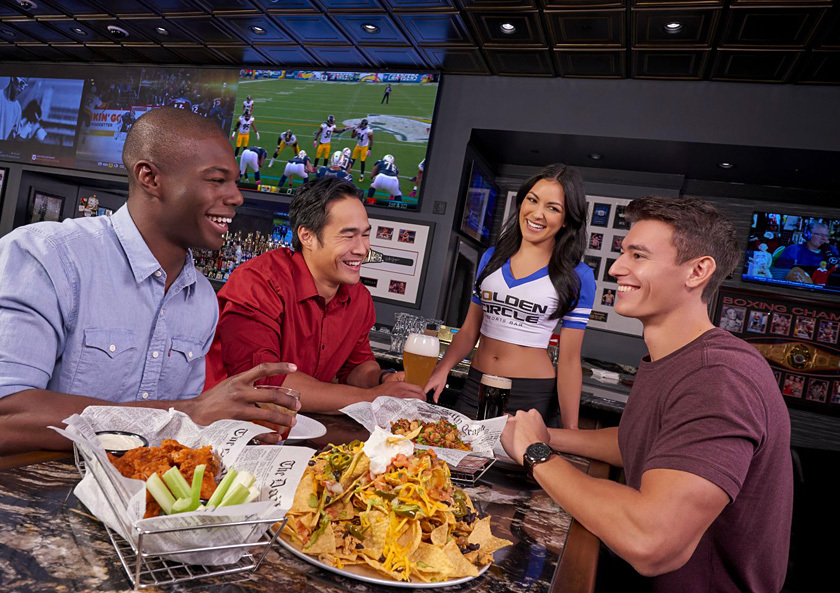 Golden Circle Sportsbook & Bar guests with server at table with nachos and wings